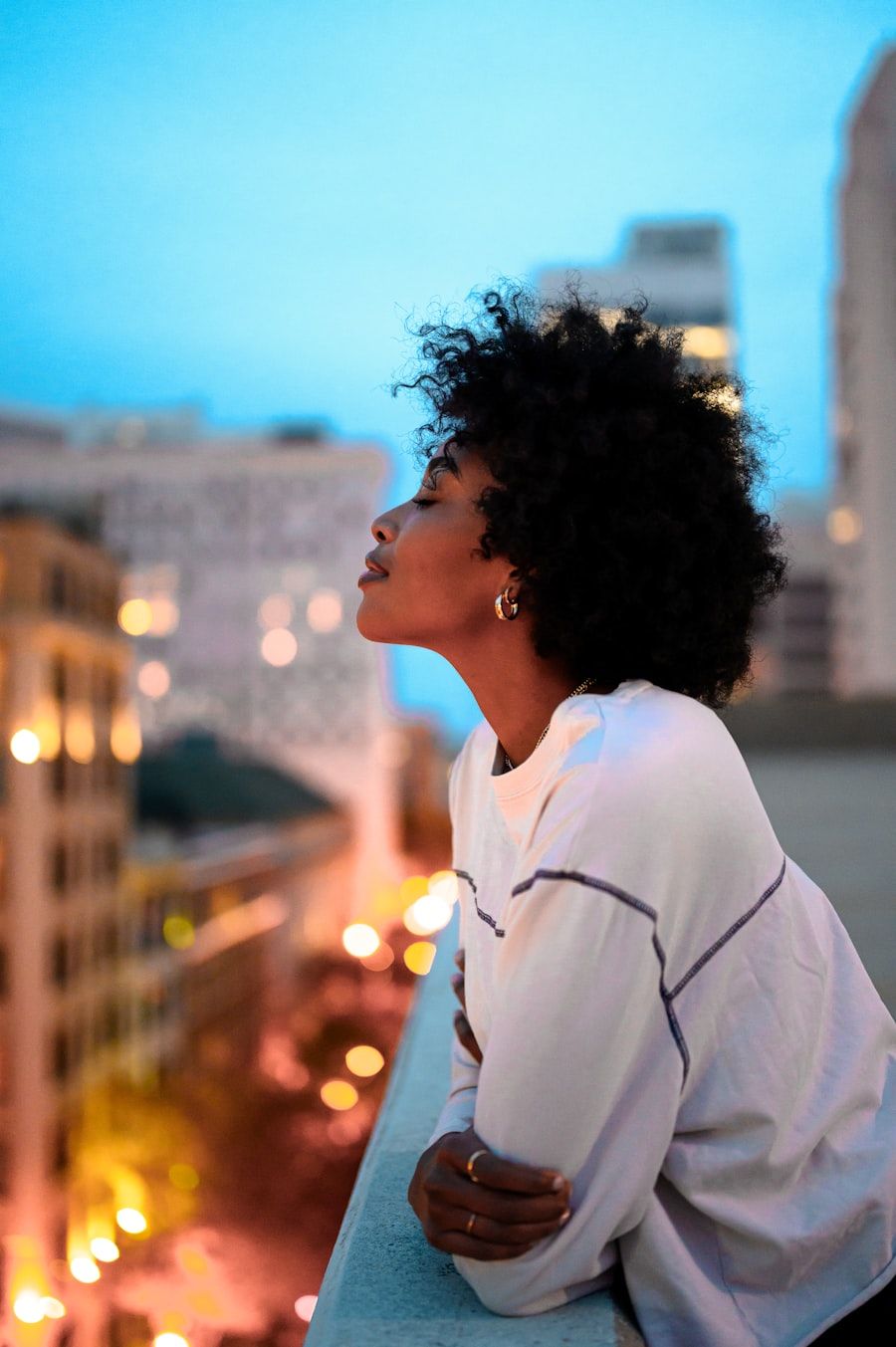 A woman on a balcony above the city at dusk