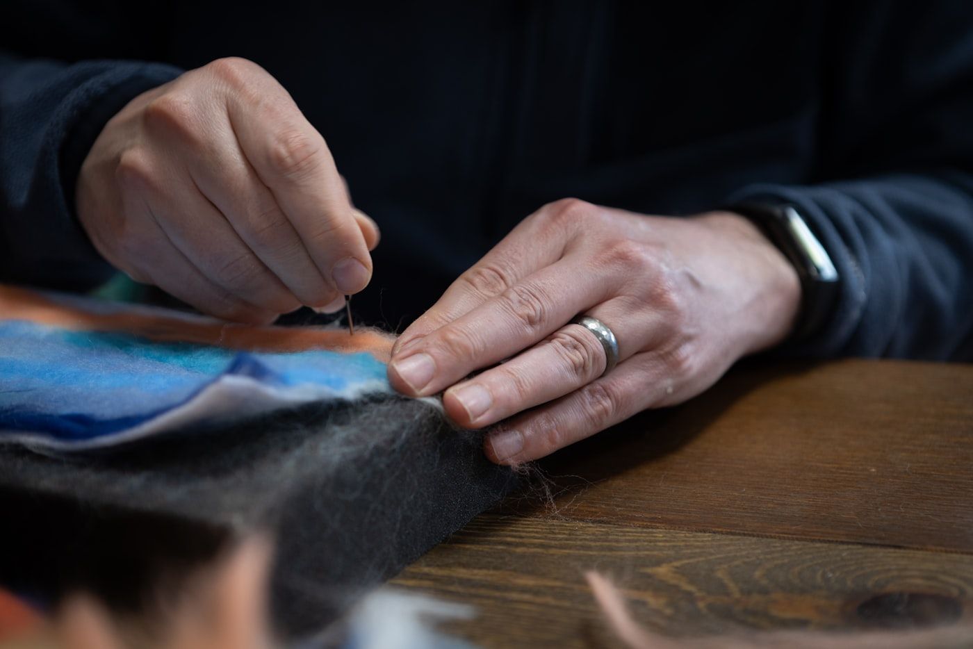 Hands stitching fabric at a workbench